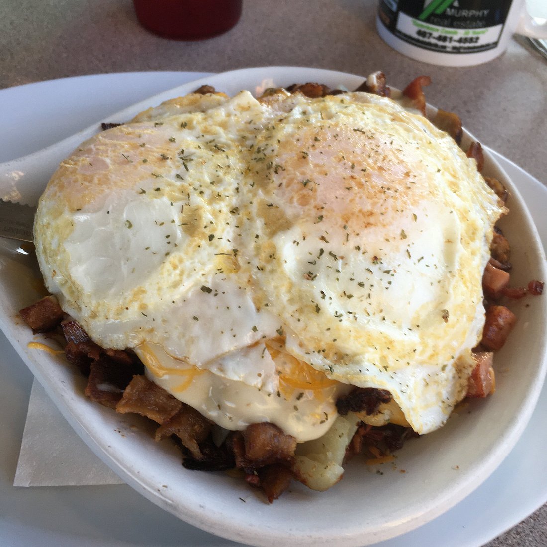 Country breakfast bowl: bacon, hash browns, two over-easy eggs